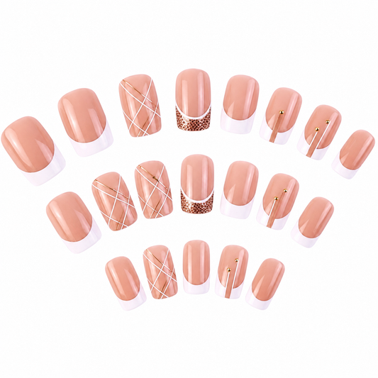 A set of press-on nails arranged in curved rows on a plain white background. The nails feature a glossy nude-peach top with white French tips and various decorative nail art designs including white crisscross lines, brown polka dots, and thin gold metallic accents.