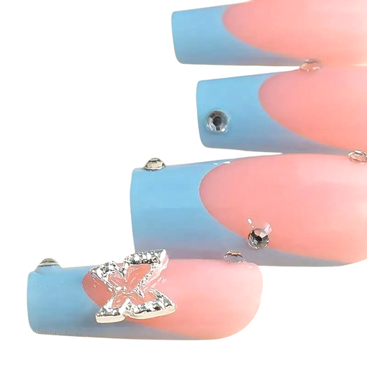 Snazzi Pink Shop Butterfly Noir long coffin press-on nails with nude base, blue tips, crystals, and butterfly charm.