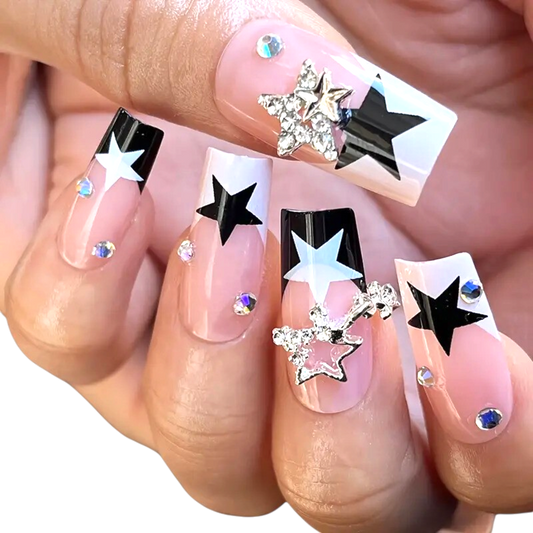 Snazzi Pink Shop long coffin press-on nails with nude base, navy blue and white star tips, and crystal star charms.