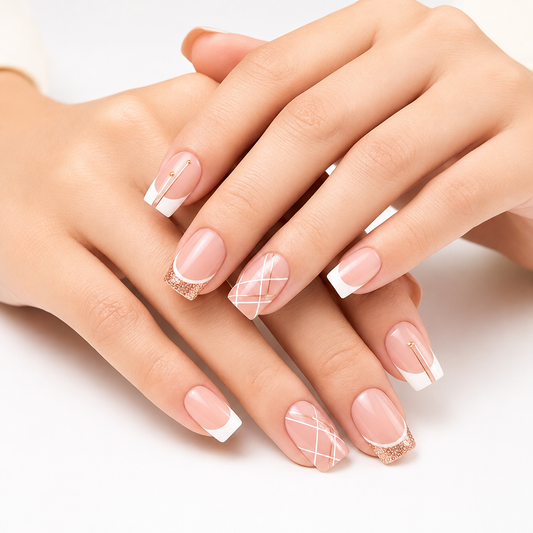 Close-up of hands with manicured fingernails featuring a soft pink base, white French tips, and delicate white line patterns on some nails, with glittery gold accents.