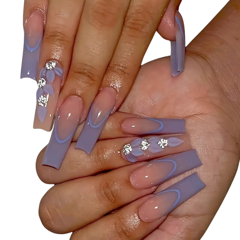 A close-up of a person's hands showcasing long, square-shaped press-on nails with a lavender and nude gradient design, French tips, and rhinestone embellishments, set against a plain white background.
