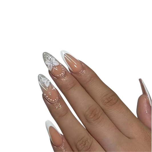 A close-up of a hand displaying long, almond-shaped nails with a glossy nude-beige base and white French tips, decorated with delicate white floral and dot patterns on the top nails.