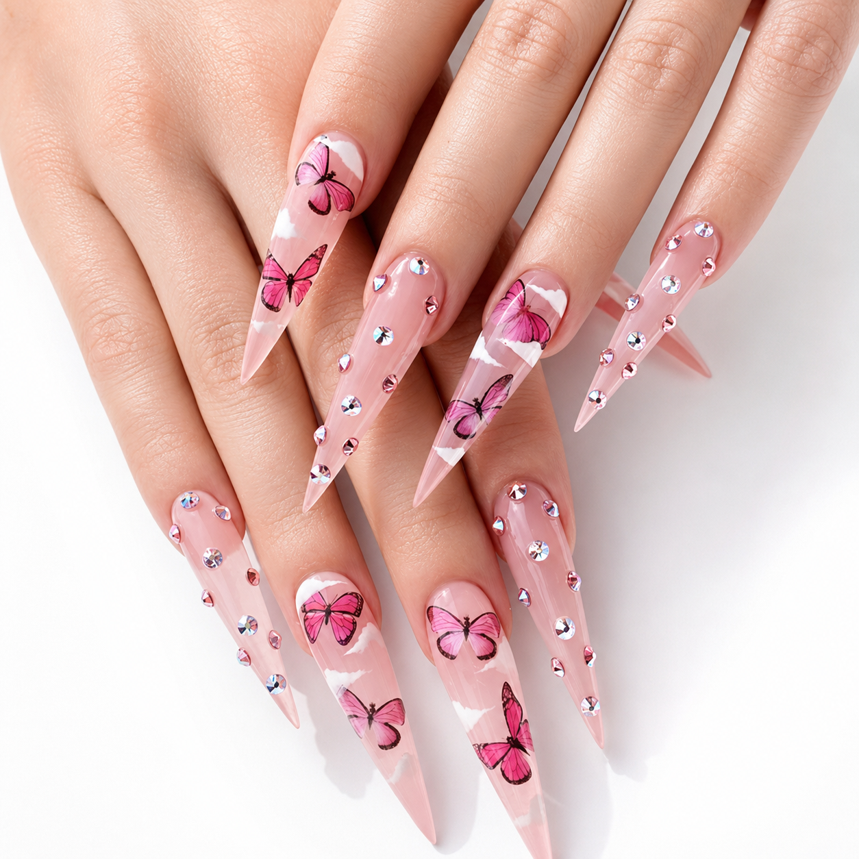 A close-up of manicured hands with long, pointed stiletto nails decorated in a pink and white butterfly pattern with small rhinestone accents.