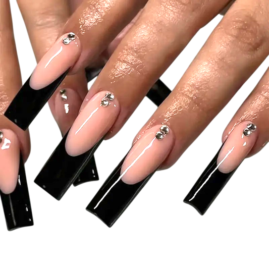 Snazzi Pink Shop extra long square press-on nails with blush nude base, black French tips, and rhinestone accents.
