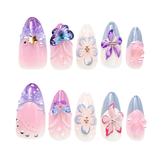 Snazzi Pink Shop Garden Daydream medium almond press-on nails with pastel floral, butterfly, and crystal accents.