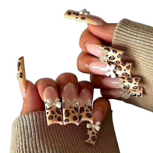 Snazzi Pink Shop extra long coffin press-on nails with leopard print and white 3D bow accents on a glossy finish