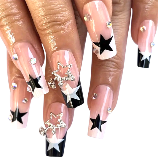 Snazzi Pink Shop long coffin press-on nails with nude base, navy star tips, crystal charms, and iridescent rhinestones