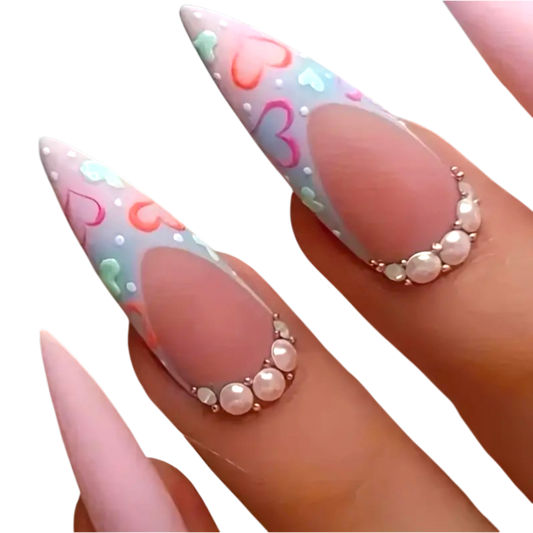 Snazzi Pink Shop long almond press-on nails with matte blush finish, pastel heart French tips, and pearl accents.