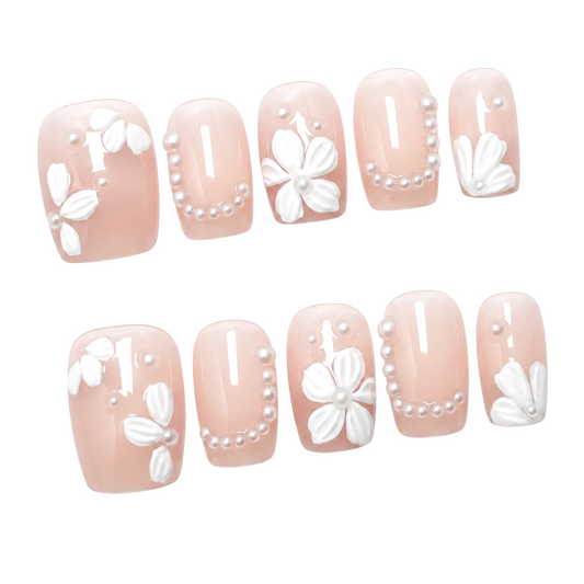 Snazzi Pink Shop Pearl Blossoms short square press-on nails with nude-pink base, white floral art, and pearl accents.