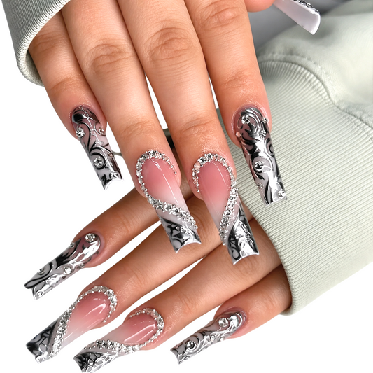 Snazzi Pink Shop extra-long coffin press-on nails with nude-ivory base, metallic silver scrollwork, and crystals.